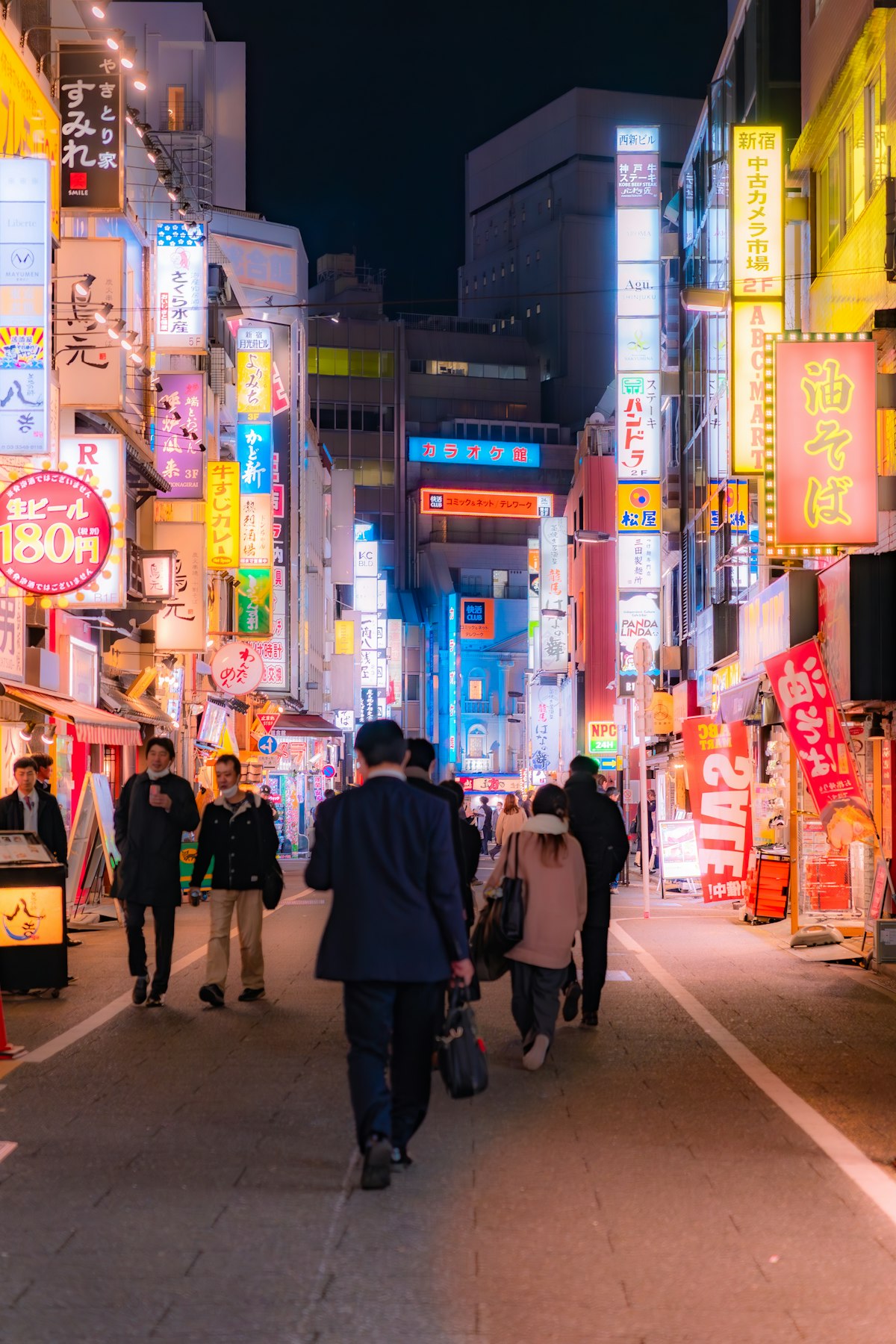 People strolling down a neon-lit street in Shinjuku Japan