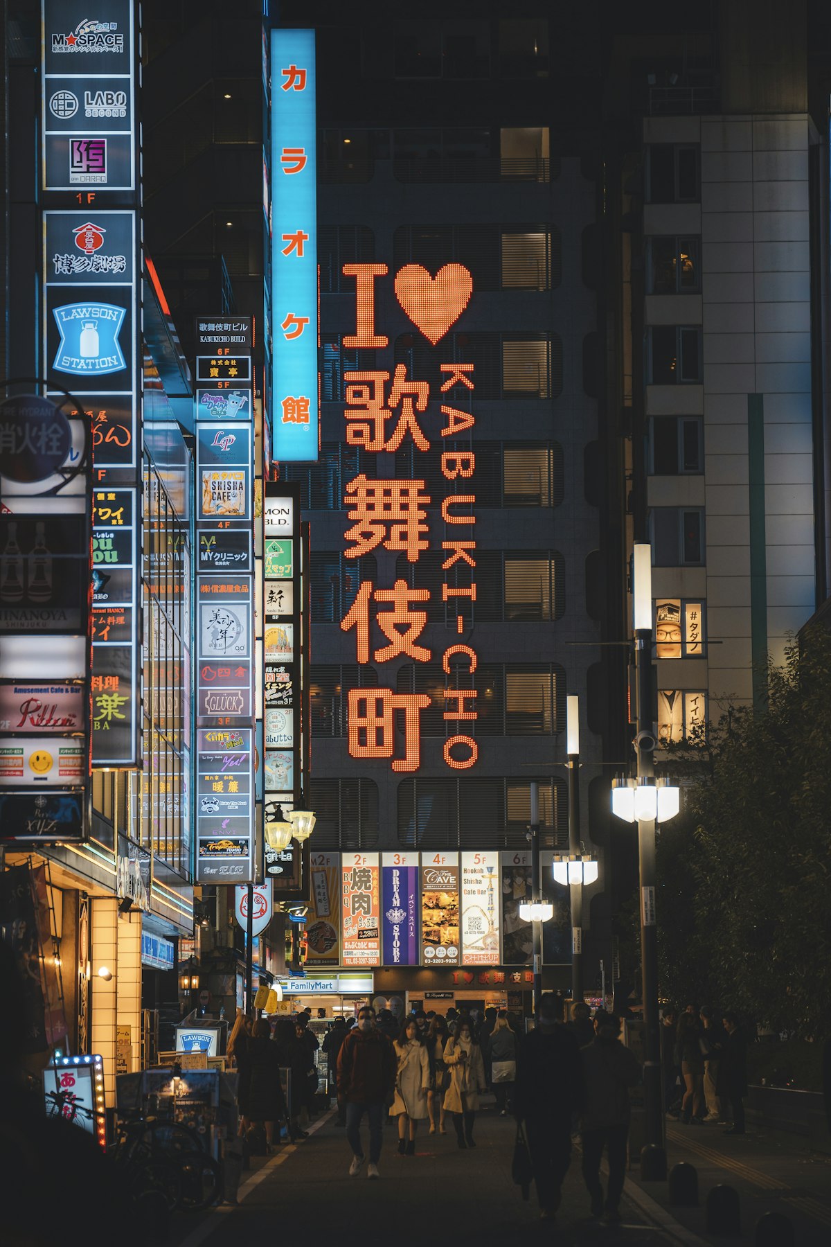 People walking under the iconic I Love Kabukicho sign at night in Shinjuku Tokyo