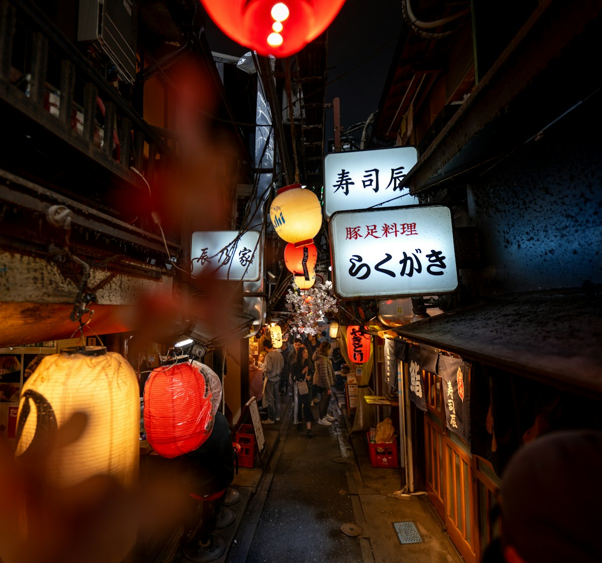 A narrow alley with hanging lanterns in Shinjuku at night