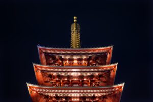 Senso-ji Temple and its five-story pagoda illuminated in red and gold against a black night sky in Asakusa