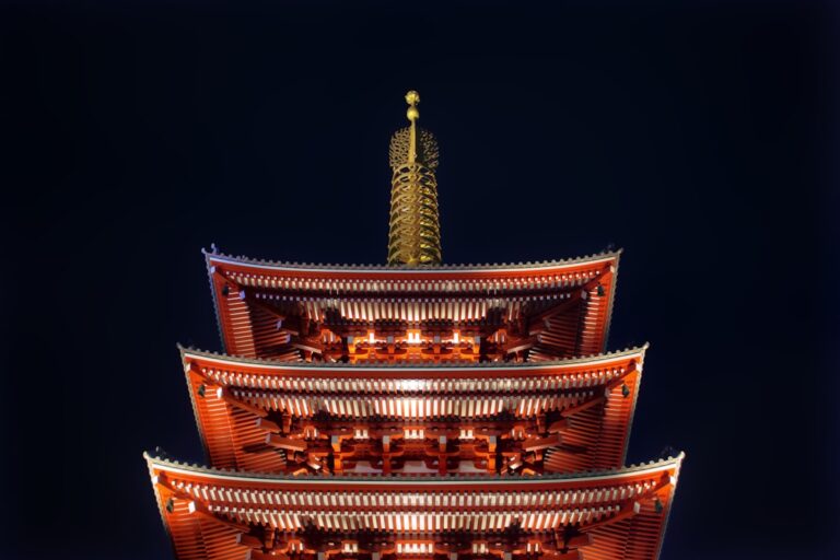 Senso-ji Temple and its five-story pagoda illuminated in red and gold against a black night sky in Asakusa