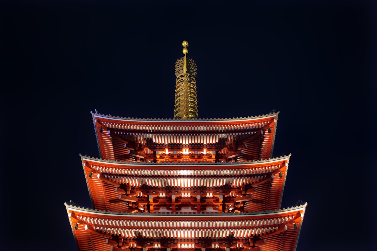 Senso-ji Temple and its five-story pagoda illuminated in red and gold against a black night sky in Asakusa