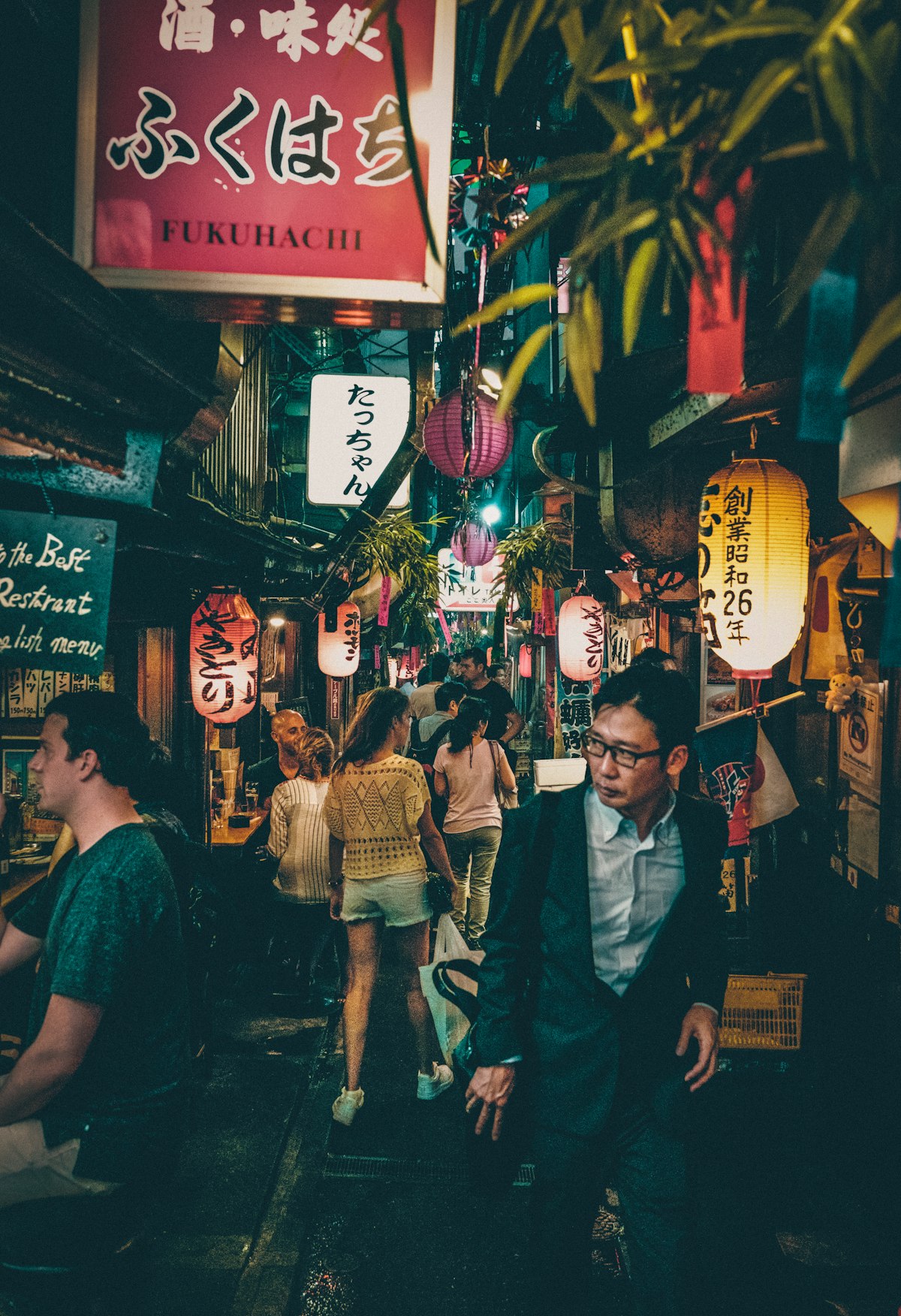 People walking through the narrow Omoide Yokocho alley in Shinjuku at nighttime