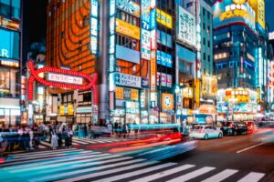 Neon-lit building signs stacked above a Kabukicho street in Shinjuku, Tokyo, where most girls bars operate on upper floors