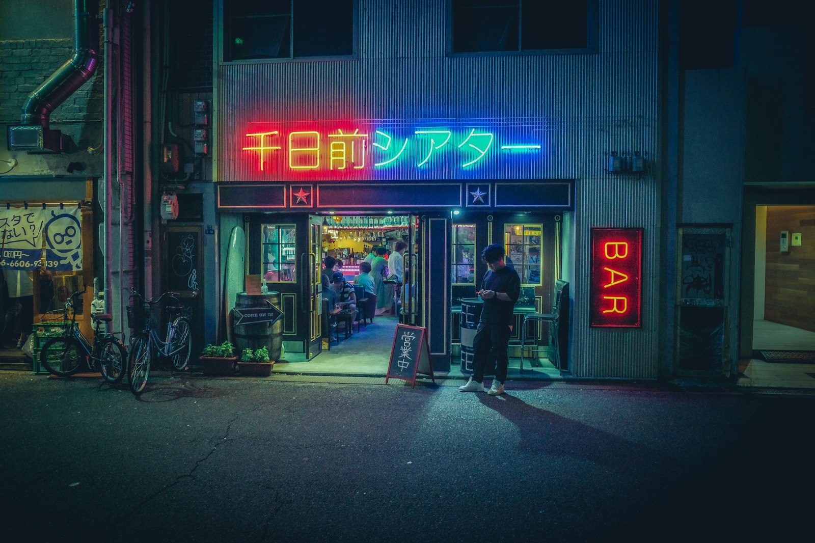 A price board posted at the entrance of a Japanese bar building, listing set charges and drink prices before customers go upstairs