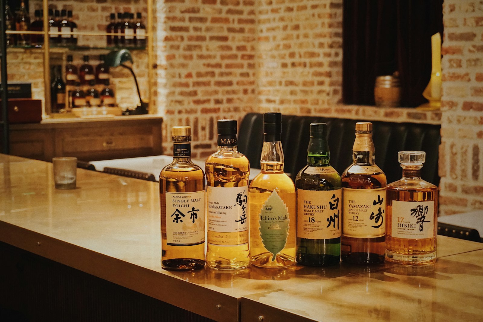 Dimly lit Tokyo bar interior with whisky glasses on a polished counter, similar to the atmosphere inside an upscale hostess club