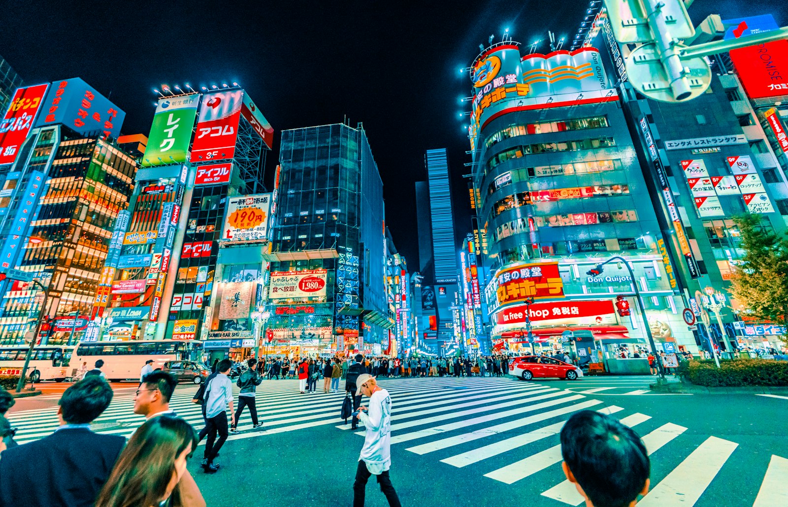 Crowds walking through a brightly lit Shinjuku street in Tokyo at night
