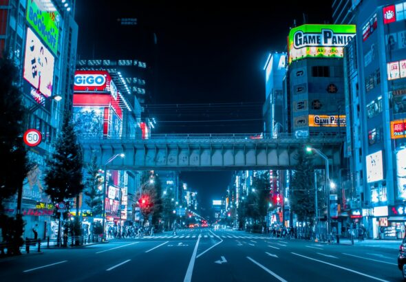 Neon signs and anime billboards lining the main street of Akihabara, Tokyo, at dusk