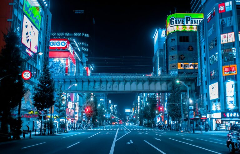 Neon signs and anime billboards lining the main street of Akihabara, Tokyo, at dusk