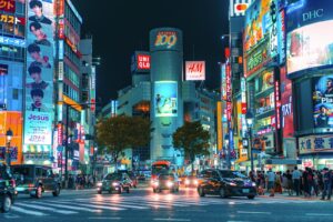 Crowds crossing Shibuya Scramble Crossing under neon signs at night, the starting point of Shibuya nightlife