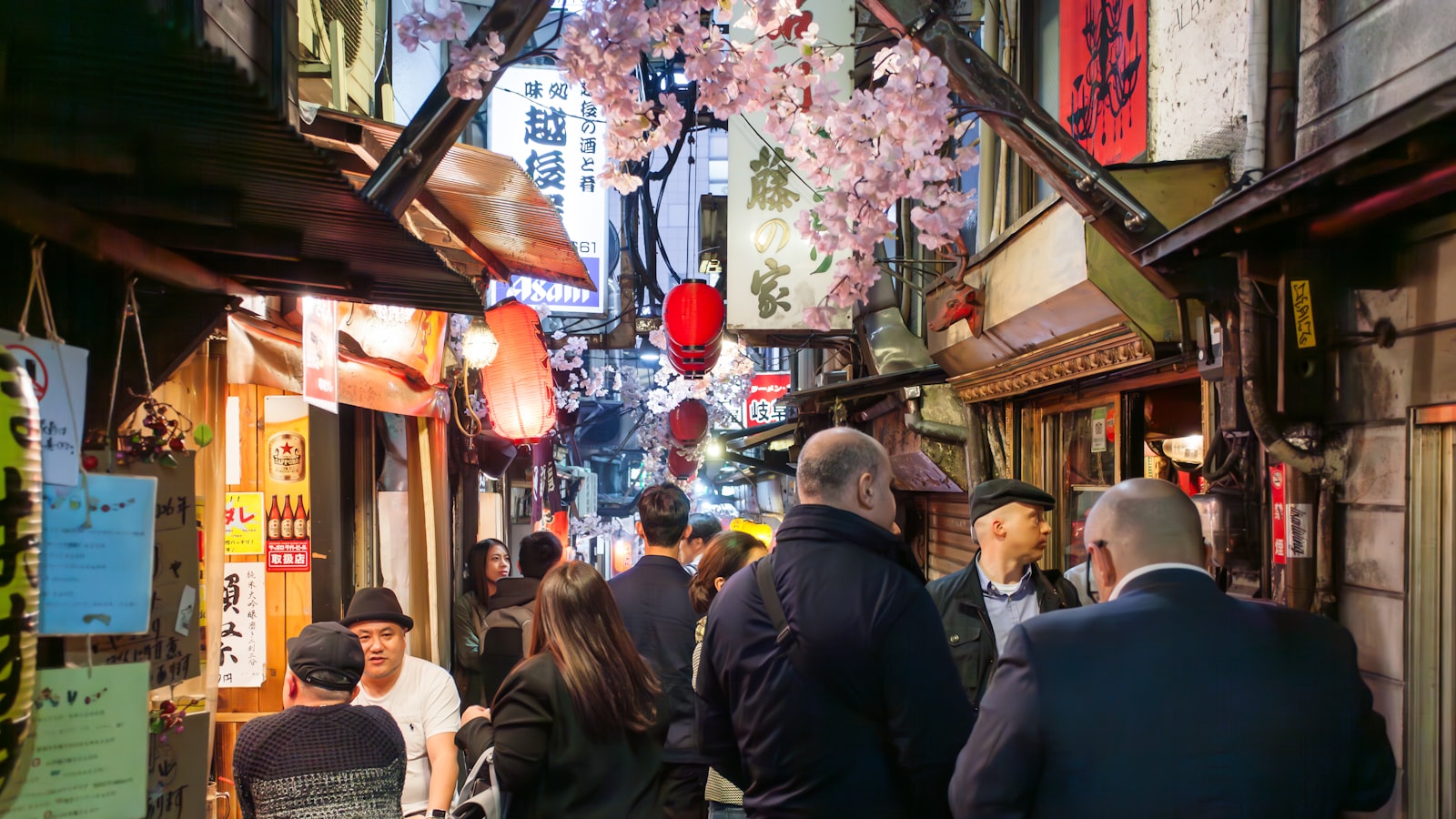 Narrow Tokyo alley lined with standing bars and red lanterns in the evening