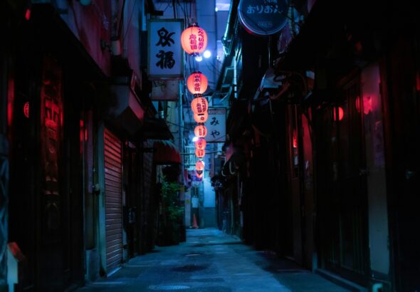A narrow Tokyo alley lined with red lanterns and glowing standing bar doorways after dark
