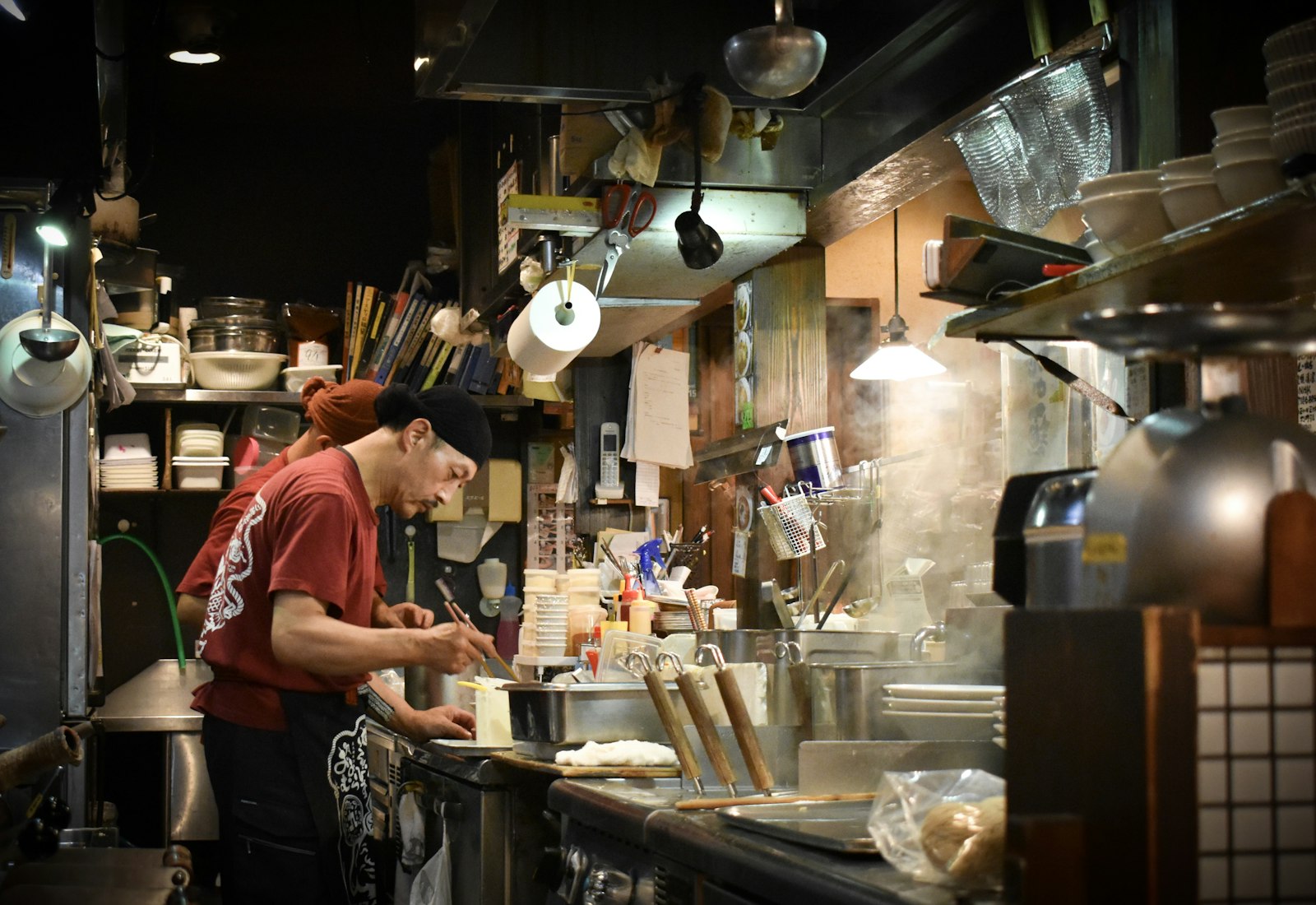 Small plates and glasses crowded along the wooden counter of a Japanese standing bar