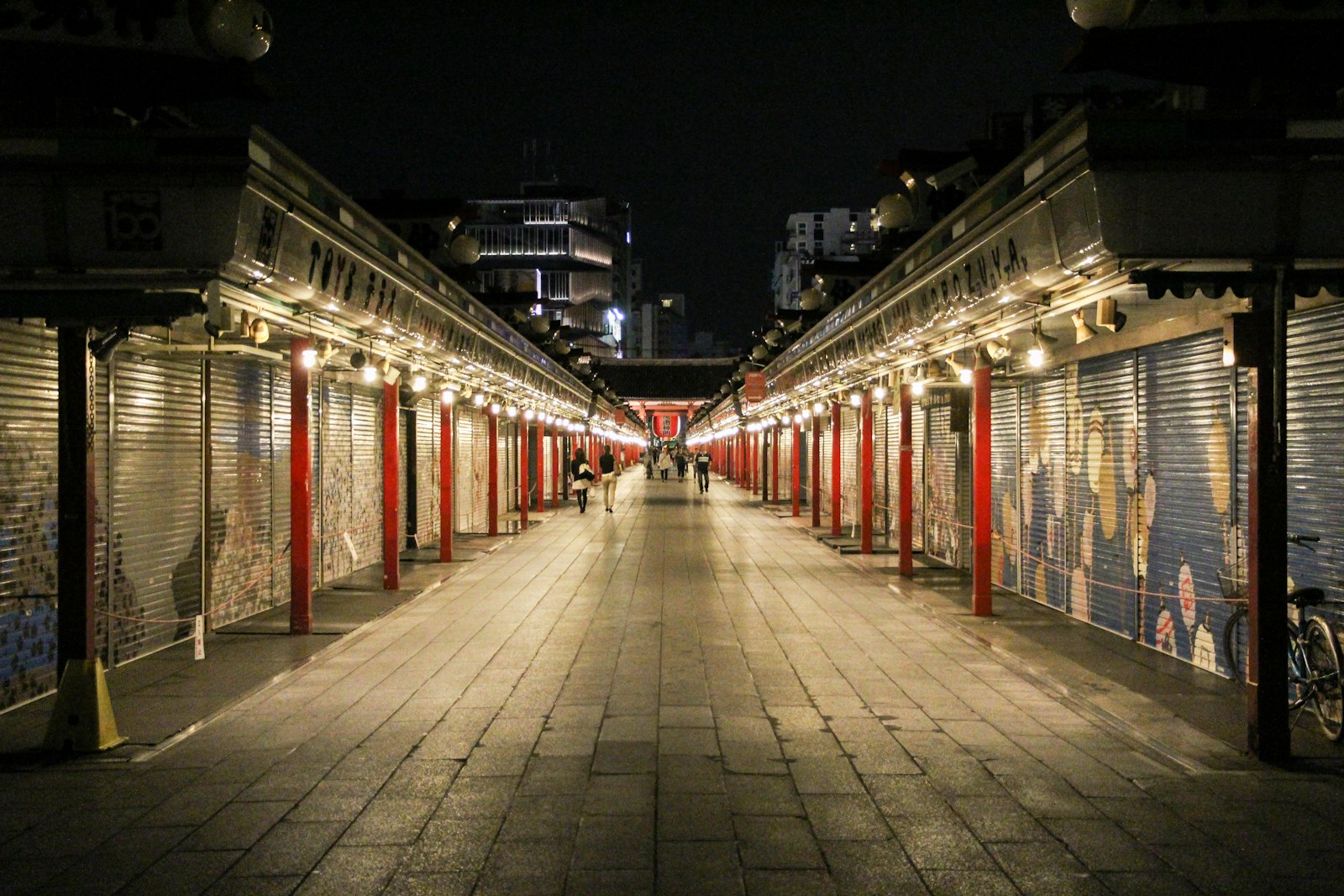 Quiet Nakamise-dori at night with shops closed and painted shutters lit by lanterns on the way to Senso-ji