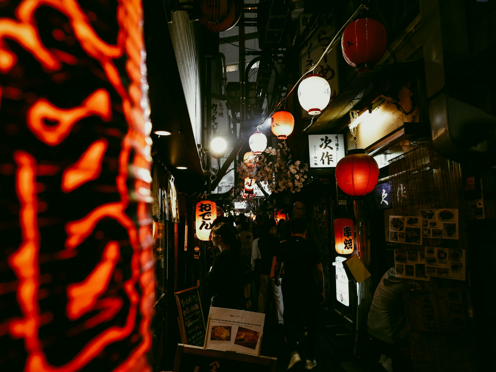 Narrow lantern-lit yokocho alley in Tokyo at night lined with tiny izakaya bars