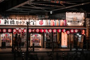 A narrow Tokyo yokocho alley at night lined with red lanterns and tiny izakaya counters
