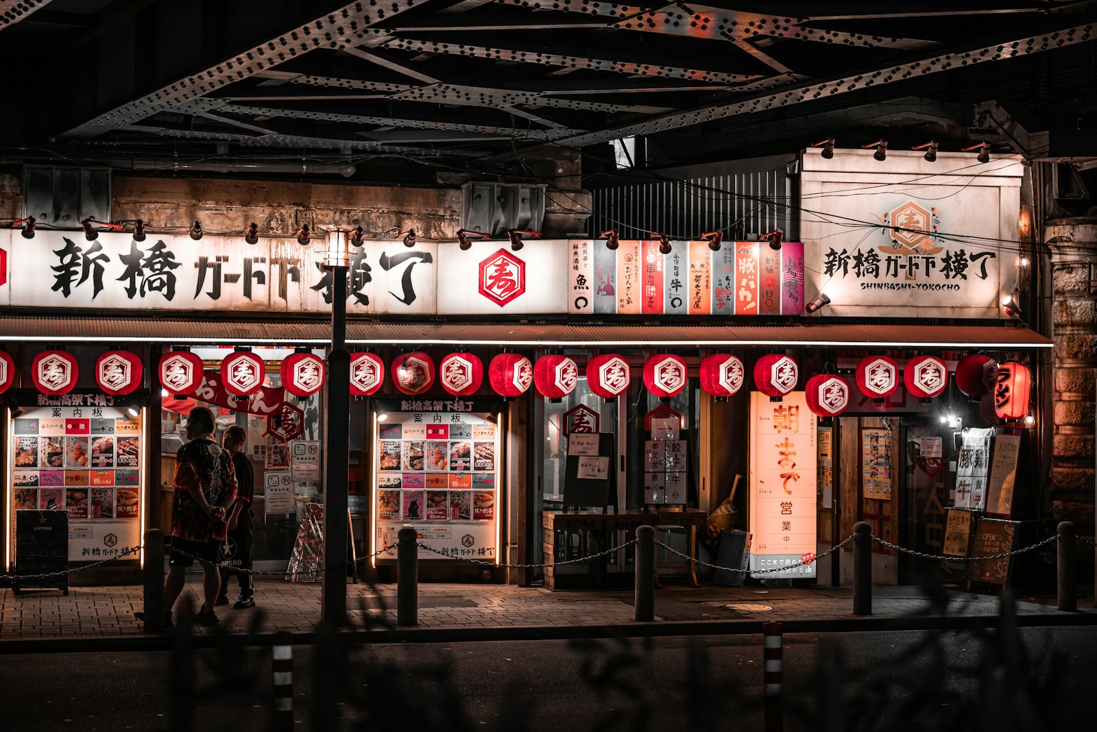 A narrow Tokyo yokocho alley at night lined with red lanterns and tiny izakaya counters