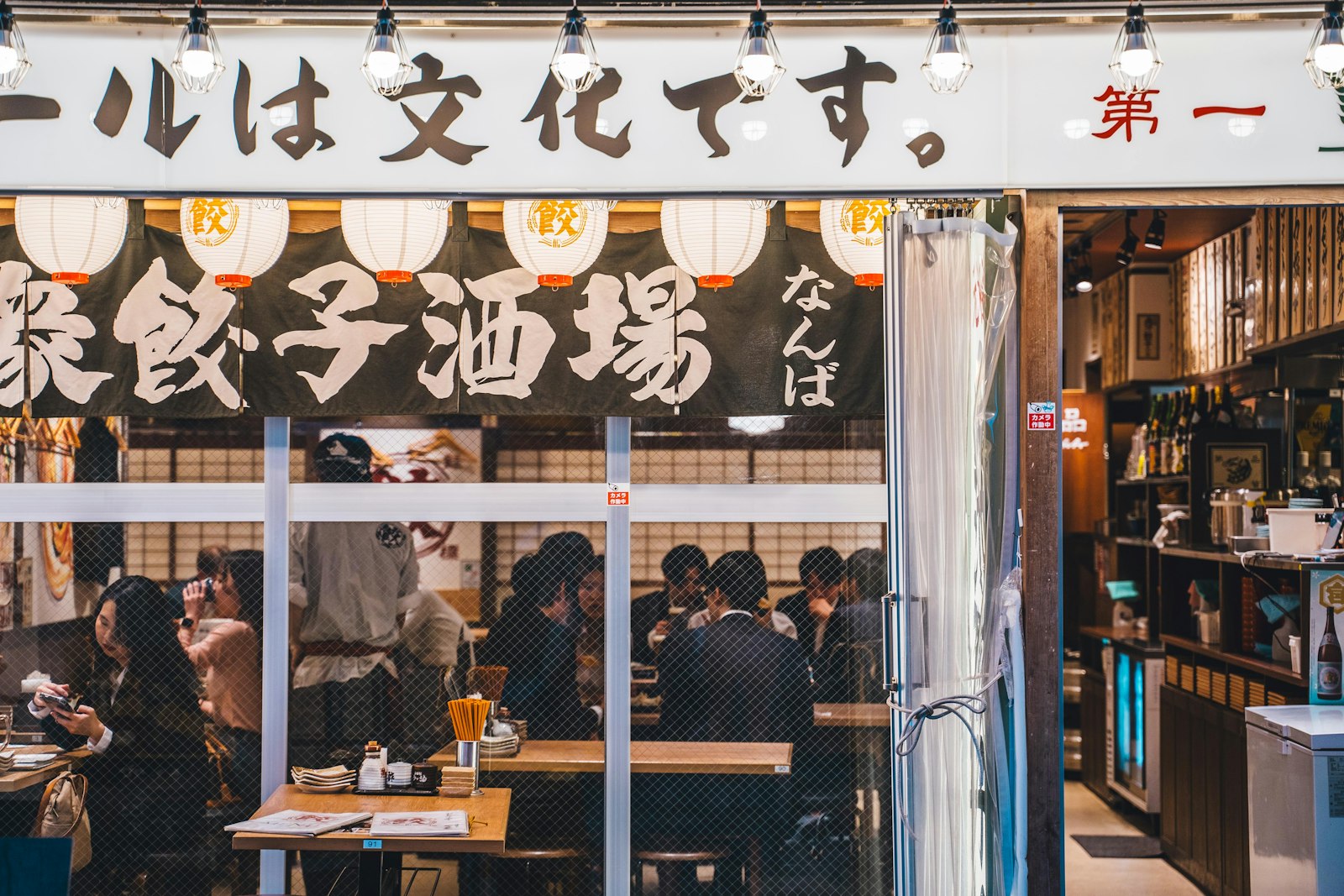 Warm-lit izakaya counter in Tokyo with drinks and small plates