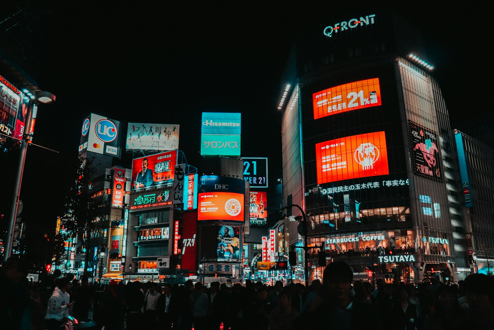A busy Shibuya street lit with neon signs late at night in Tokyo