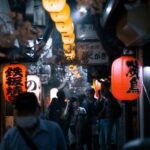 Lantern-lit alley of Omoide Yokocho in Shinjuku at night, lined with tiny yakitori counters