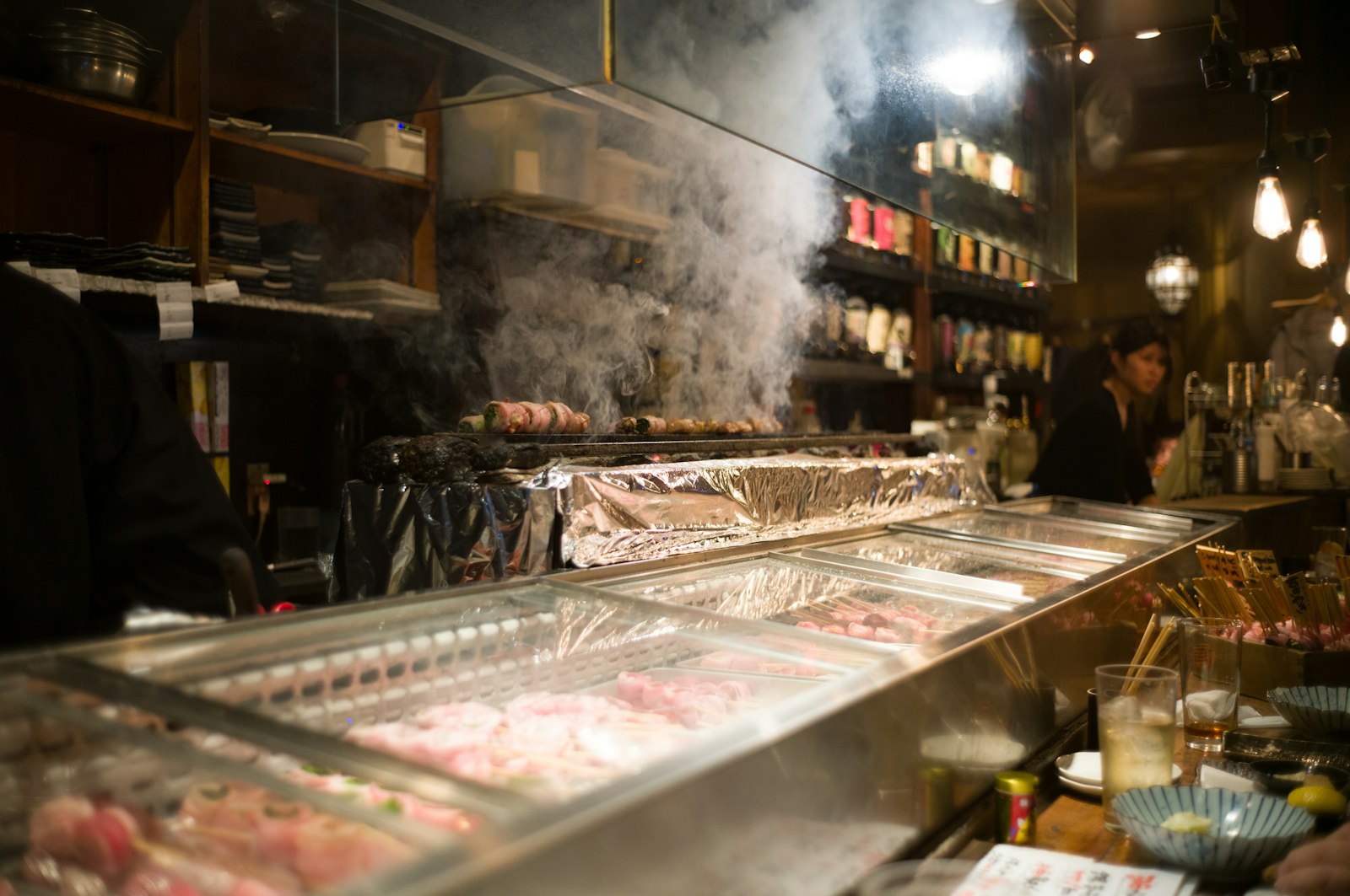 Yakitori skewers grilling at a small counter izakaya in a Tokyo alley