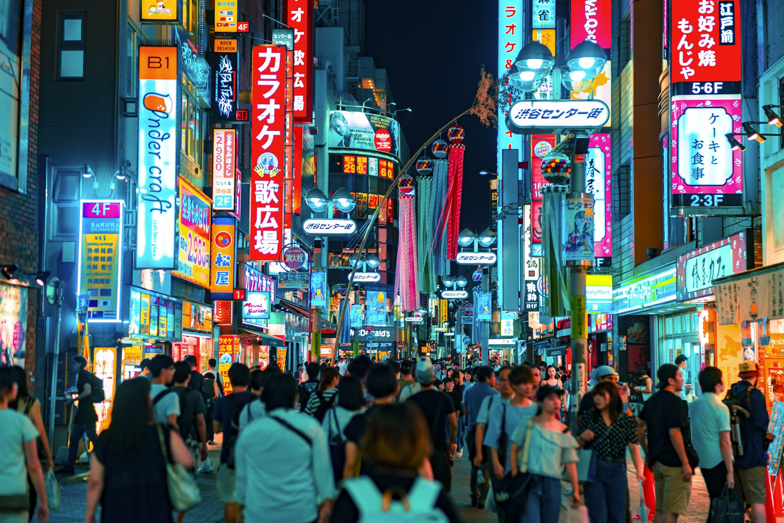 Crowds moving through a Tokyo street at night before the last trains stop running