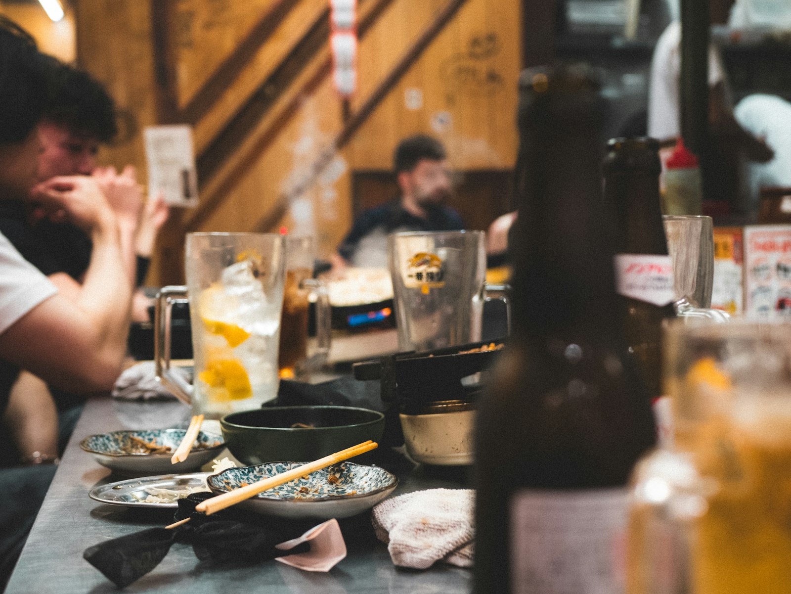 Bartender pouring a drink at a small Tokyo counter bar with an English menu on the bar