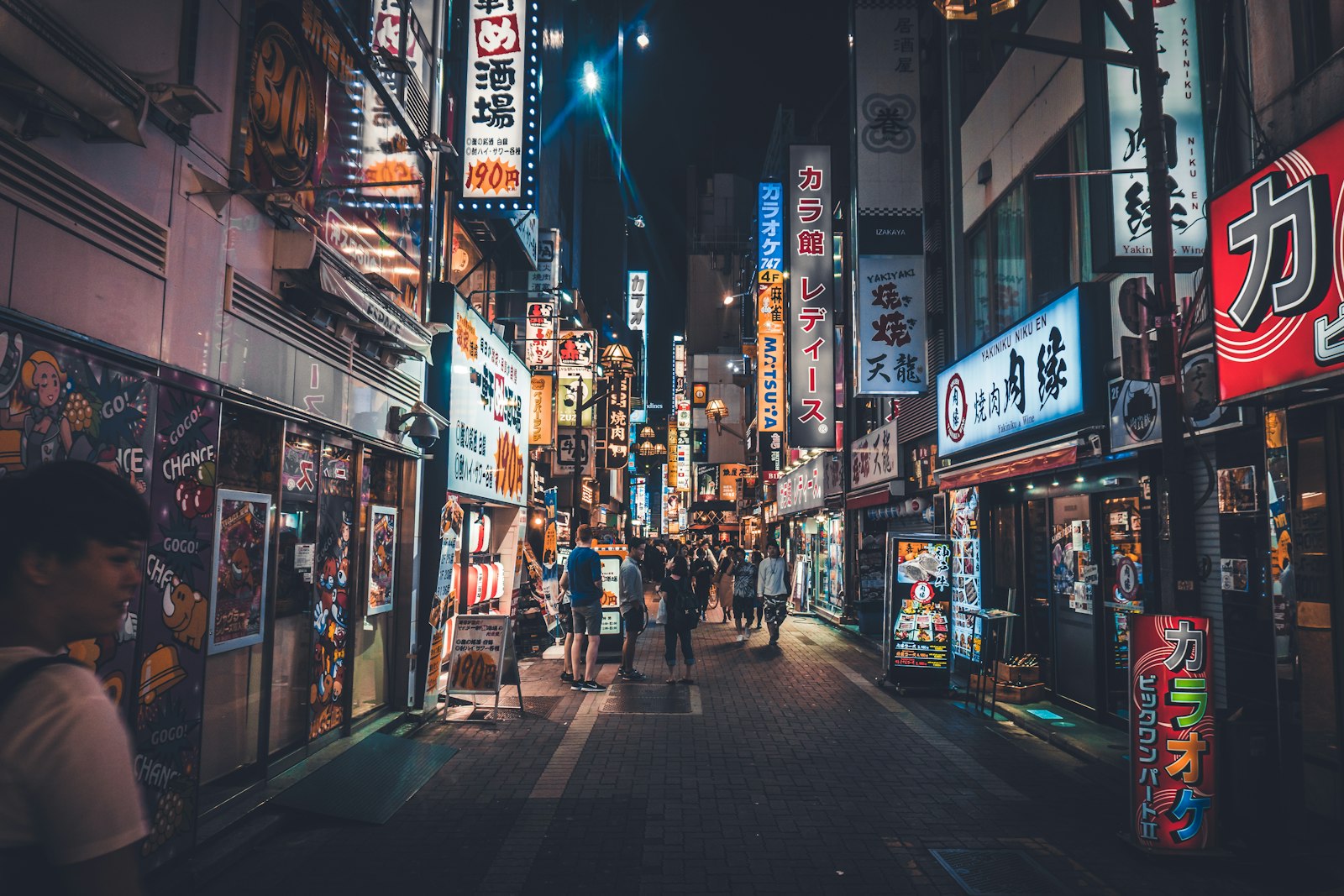 Stacked neon signboards on a Tokyo building listing the small bars on each floor