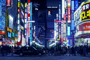 Crowds walking under neon signs on a busy Tokyo nightlife street at night