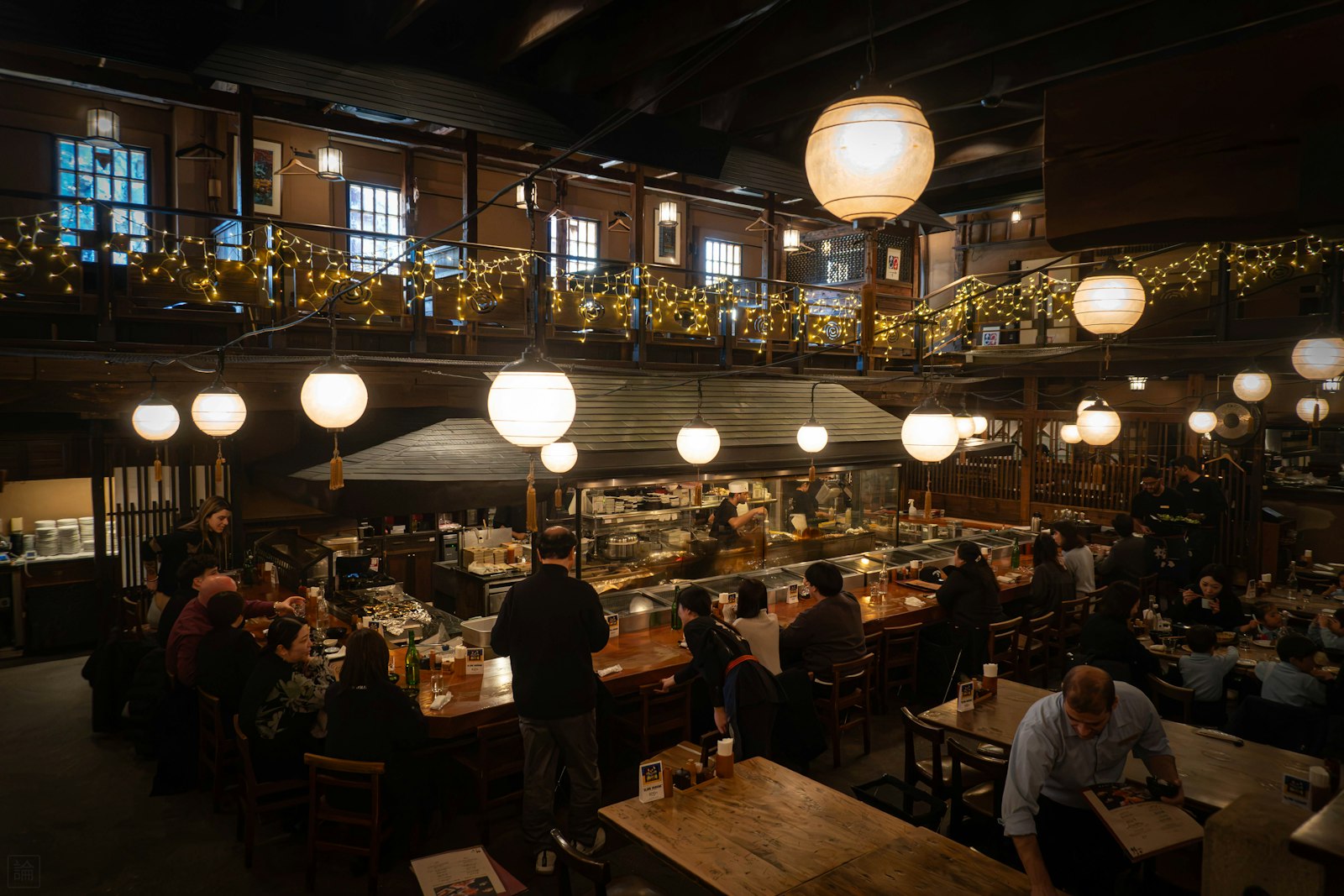 Warm interior of a Tokyo izakaya with red lanterns and counter seating