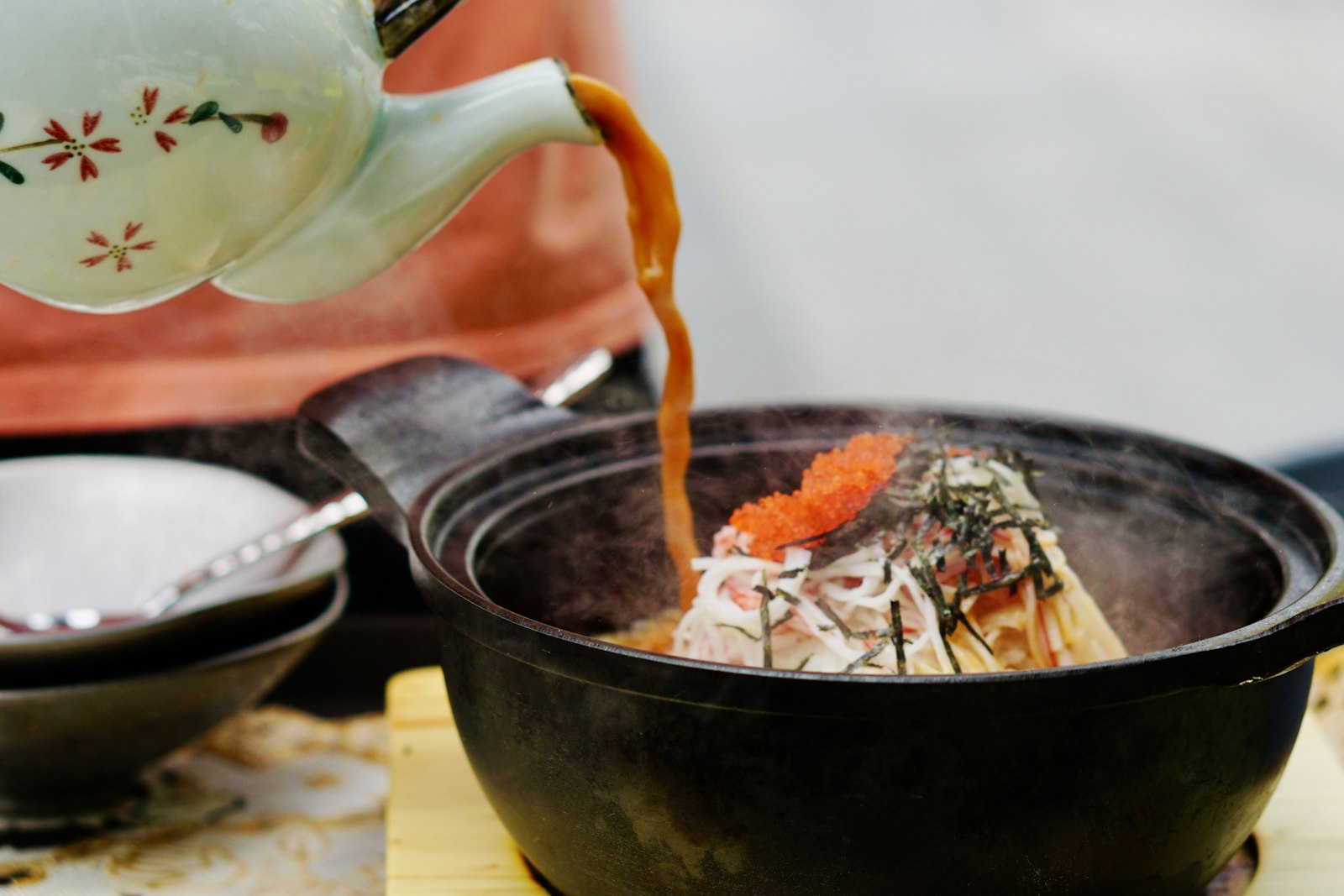 Warm sake poured from a tokkuri flask into a small ochoko cup at a Tokyo izakaya