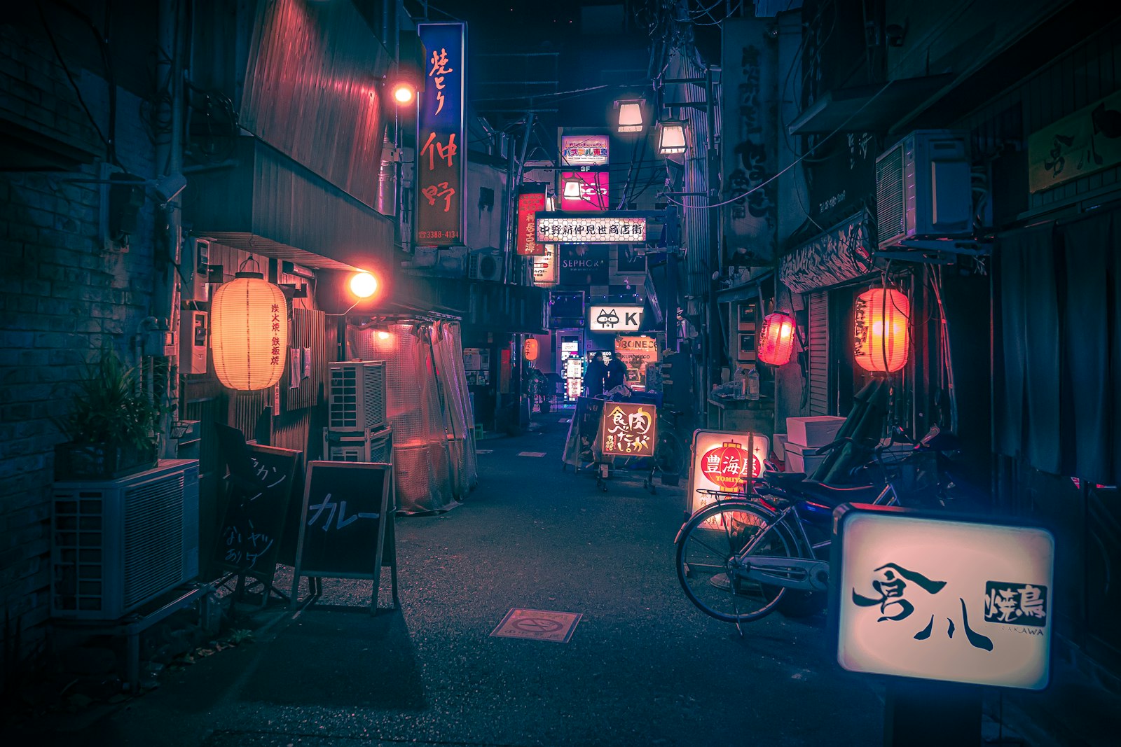 A Tokyo backstreet at night with lanterns outside small standing bars, where kakuuchi fits into a night of local drinking