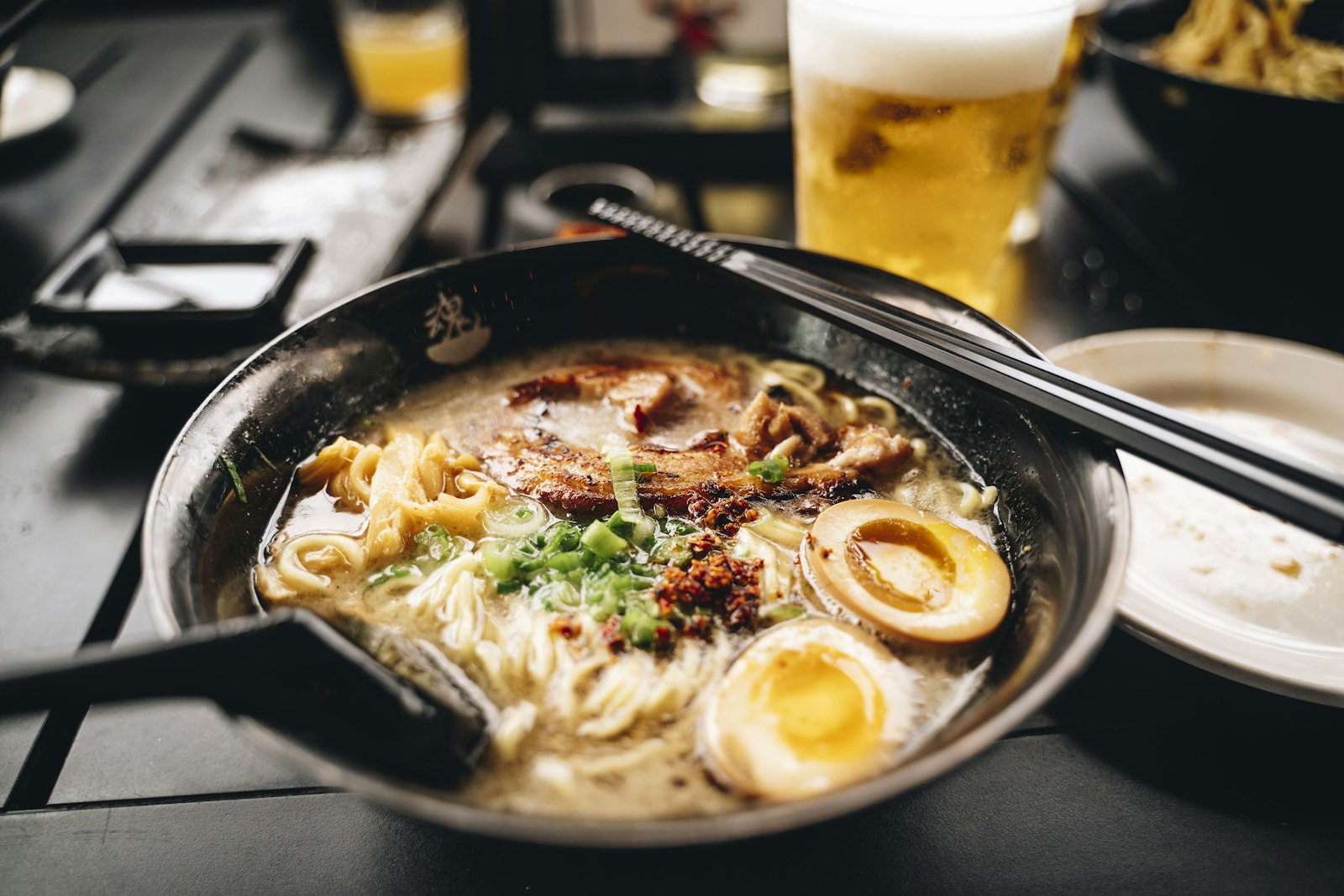 A steaming bowl of tonkotsu ramen with chashu pork on a wooden counter