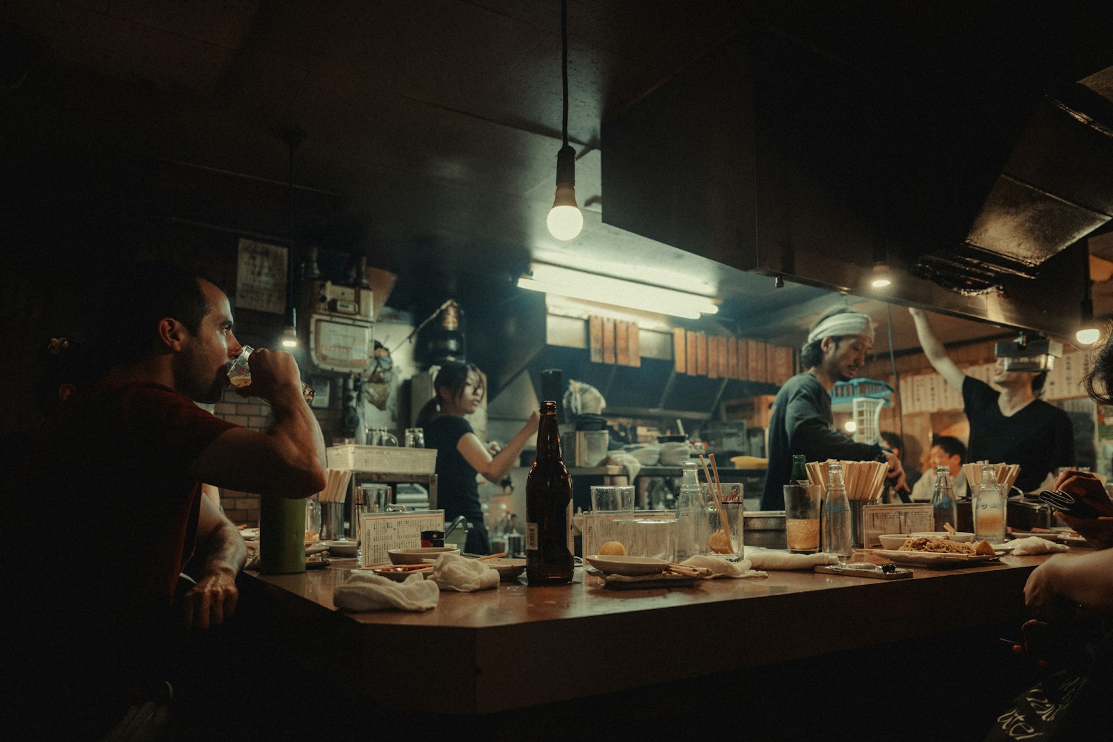 Bartender working behind a small wooden counter in a tiny hidden bar in Shibuya, Tokyo