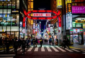 Neon signs towering over a crowded Kabukicho street in Shinjuku at night