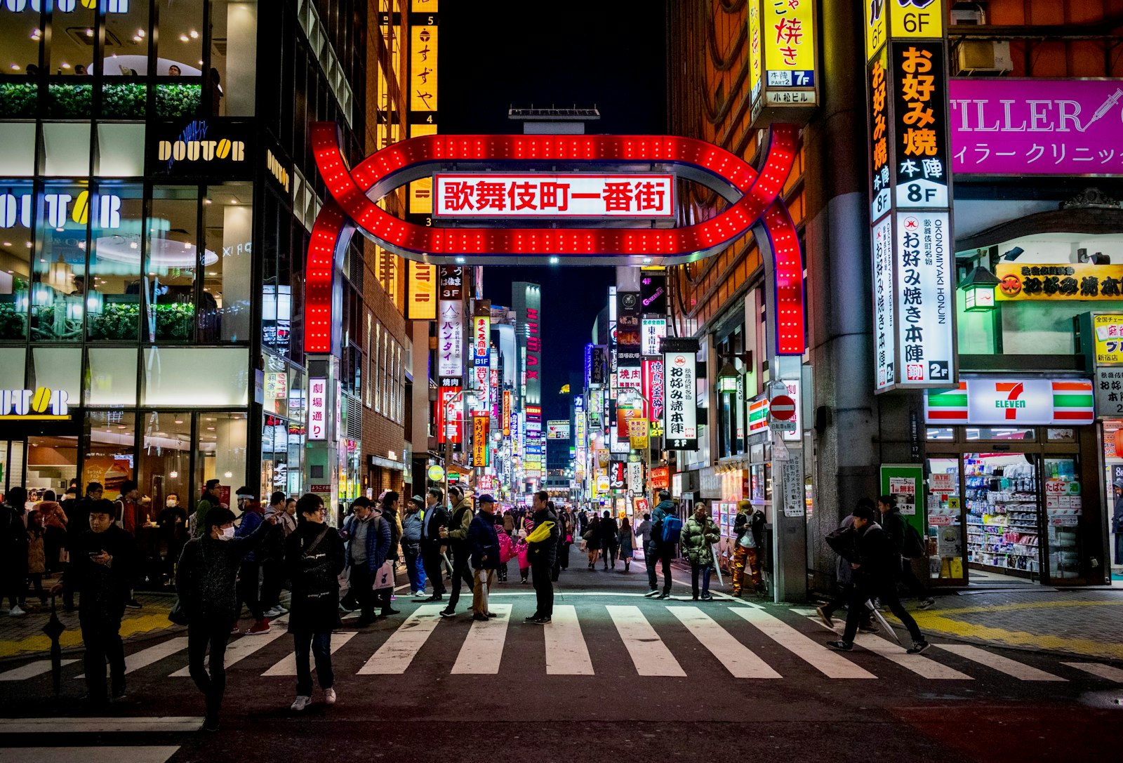 Neon signs towering over a crowded Kabukicho street in Shinjuku at night