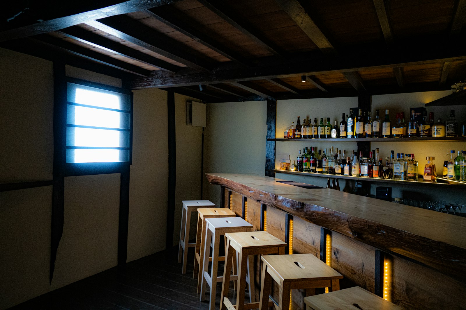 The counter of a small Japanese bar, with kept bottles lined up behind it — the standard layout of a sunakku
