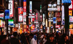 Group of friends walking down a neon-lit Shinjuku street at the start of a Tokyo bachelor party night