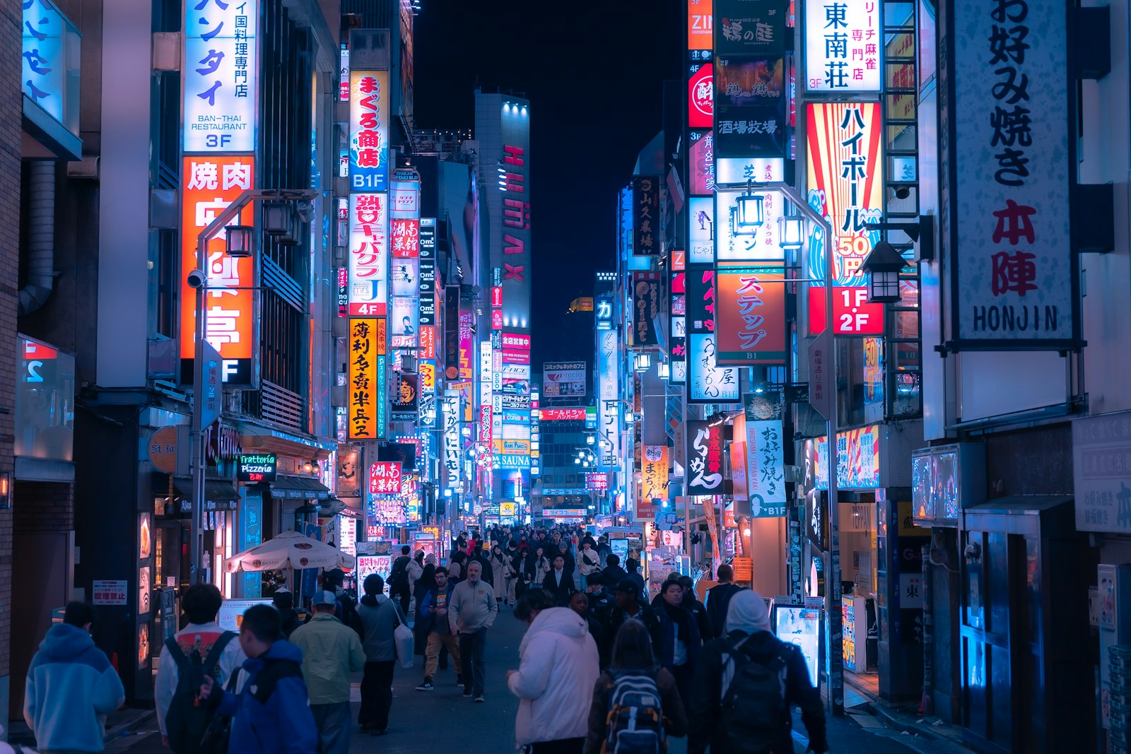 Foreign tourists walking down a neon-lit Shinjuku street on a Tokyo night tour