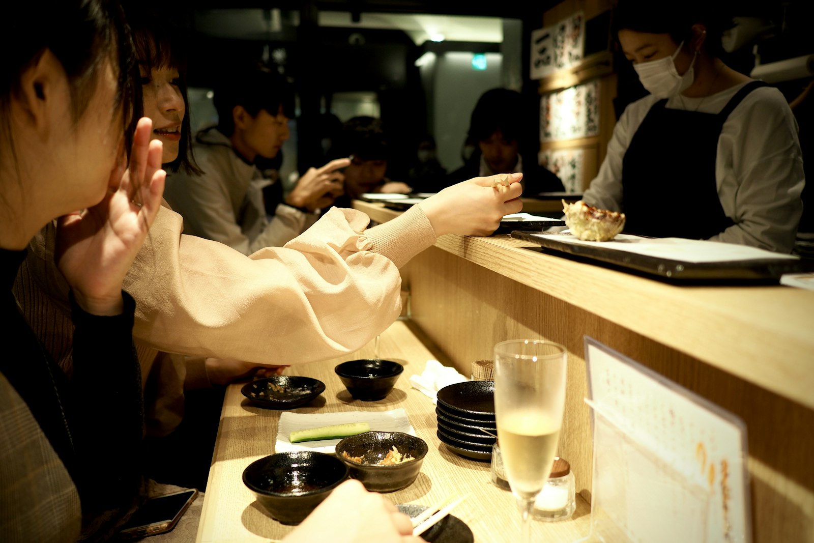 Guests chatting with a bartender across an izakaya counter in Tokyo during an evening tour