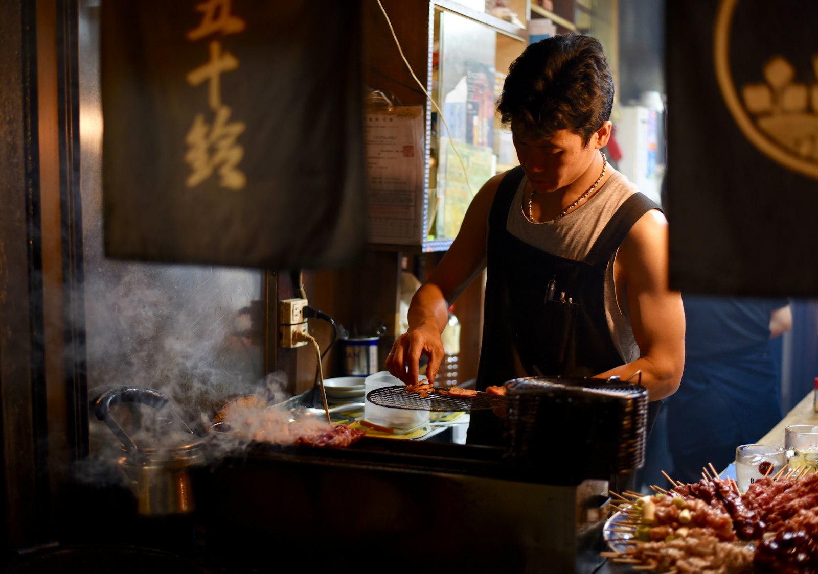 Small izakaya counter with yakitori on the grill, a typical stop on a Tokyo bar hopping tour