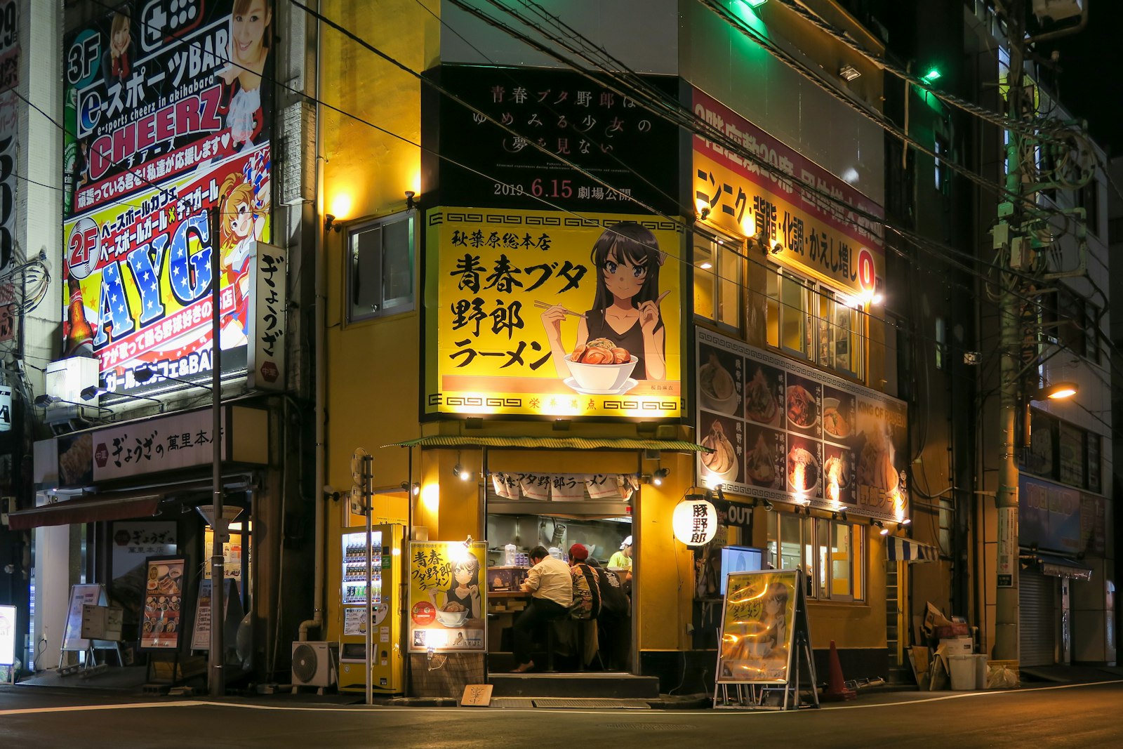 Customers sitting at a small bar counter in a Tokyo izakaya at night