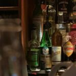 Bartender pouring Japanese whisky at a Tokyo bar counter lined with bottles, the first stop on a Tokyo whisky bar tour