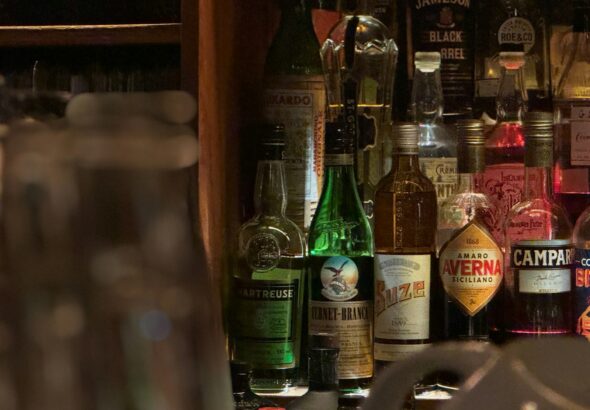 Bartender pouring Japanese whisky at a Tokyo bar counter lined with bottles, the first stop on a Tokyo whisky bar tour