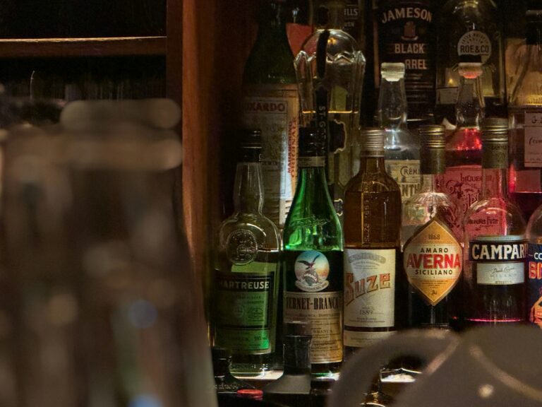 Bartender pouring Japanese whisky at a Tokyo bar counter lined with bottles, the first stop on a Tokyo whisky bar tour