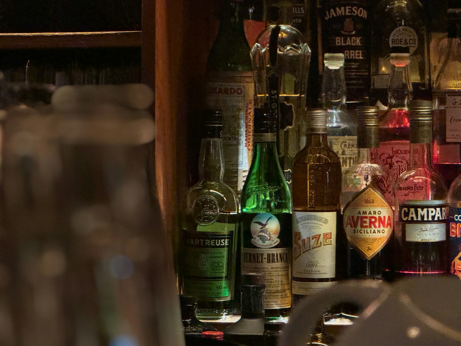 Bartender pouring Japanese whisky at a Tokyo bar counter lined with bottles, the first stop on a Tokyo whisky bar tour