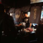Smoke and red lanterns in a Shinjuku yakitori alley on a Tokyo night