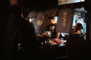Smoke and red lanterns in a Shinjuku yakitori alley on a Tokyo night