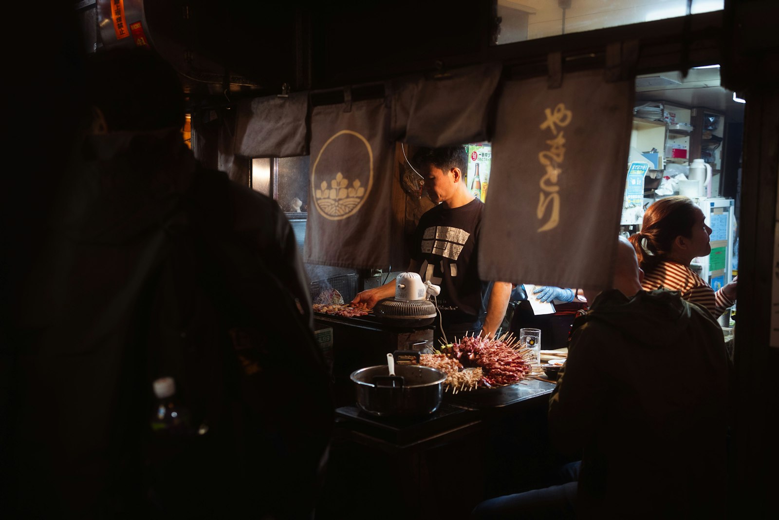 Smoke and red lanterns in a Shinjuku yakitori alley on a Tokyo night