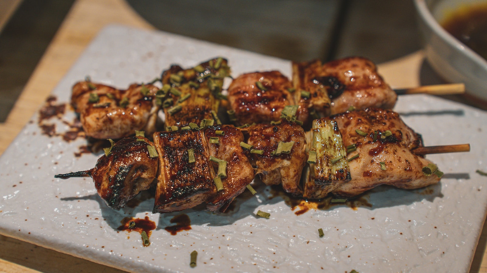 Plate of grilled yakitori skewers served at a small Japanese izakaya counter